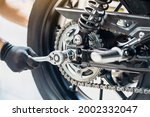 Mechanic using a wrench and socket to Remove and Replace Rear Motorcycle Wheel  , maintenance, repair motorcycle concept in garage .selective focus