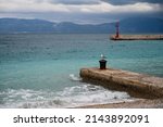 Waves on the sea at cloudy winter day. Gradac, Croatia. Lighthouse and dock. Adriatic Sea at cloudy day. Seagull.