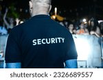 Small photo of The security guard wears a T-shirt with the inscription security. A security guard stands in front of the audience during a music festival.