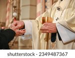The priest gives the sacramental bread to the faithful during the mass. Catholic priest giving the Communion bread in cathedral. 