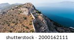 Greece, Nafplio city, Palamidi castle, Nauplion  landmark on a steep cliff, over old town, aerial drone view. Blue sky and calm sea background.