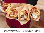 Small photo of Shawarma, Gyro pita. Greek food, sliced meat, potato, tomato and tzatziki, paper wrap served in a plate, close up view.