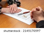 Small photo of Divorce agreement, marriage dissolution documents. Man and woman hands, wedding rings and legal papers for signature on a wooden table, lawyer office