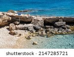 Stone stair goiing to the rocky beach, Koufonisi island, Cyclades, Greece. Nudism is forbidden sign in English and Greek text sign. Calm Aegean Sea blue, turquoise transparent water, sunny day
