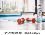 Yoga mat and a pair of weights dumbbells on wooden floor