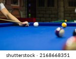 Billiard pool game in progress, player aims to shoot balls with cue