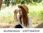 Small photo of Women tourists women white skin lovely brown hair wearing a basketry hat wear white shirt wearing black pants in hand have a camera traipse photograph nature.