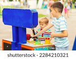 Small photo of Children playing whack a mole arcade game at an amusement park