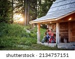 Small photo of A young couple in love spending time together at the cottage porch in the forest on a beautiful day. Vacation, nature, cottage, relationship