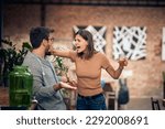 Small photo of Young couple in a bar having an argument. Woman mad at man and holding his mouth shut.