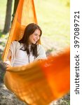 Small photo of Likeable young woman lying and enjoying in orange hammock outdoor