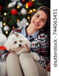 Small photo of Young cheerful woman with her puppy Meltzer for Christmas