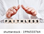 Small photo of Man holding his hands over the wooden cubes with the word faithless. Disbelief or unfaithful concept.