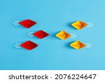Small photo of Confrontation, competition, opposition or business challenge concept. Red and yellow paper boat fleet encounter on blue background.