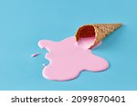 Pink ice cream melting and spilling from the waffle cone on pastel blue background. Minimalistic summer food concept.