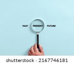 Small photo of Male hand holds a magnifier focusing on the present time alongside the past and future. To focus on the current situation, positive thinking mindset concept.