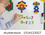 Little preschooler girl on magnetic interactive white borad is studying addition and subtraction in math lesson. Education School Preschool concept.