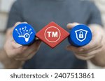 Man holding multi-colored blocks with icon sees trademark sign: TM. Trademark ( TM ) copyright or patent business industry technology web concept. Trade mark protection.