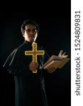 Small photo of Dark tone, rim light - Priest show lighting crucifix while holding bible to exorcise ghost on black background