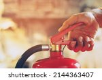 Small photo of hand presses the trigger fire extinguisher available in fire emergencies conflagration damage background. Safety