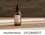 One cosmetic dark amber glass bottle with white lable on wooden table. Closeup, copyspace. Beauty blogging, salon treatment concept, minimalism brand packaging mock up