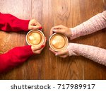 Two female hands holding cup of coffee a wooden vintage table in a coffeeshop, friend drink coffee