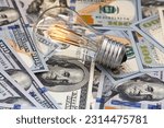 Small photo of Incandescent light bulb on US 100 dollar background for desing purpose