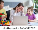 Small photo of Young women works at home with laptop, talking on phone, along with two children.Children want to communicate with mother, make noise and interfere with work.Self-isolation during coronovirus pandemic