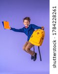 Small photo of cheerful mischievous schoolboy in uniform with backpack and books jumps on purple background. Dynamic images that go back to concept school. beginning holidays. Back to school. boy is ready to study.