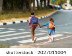 Small photo of girl and boy with backpacks carefully cross road on pedestrian crossing on their way to school. Traffic rules. Walking path along zebra in city. concept of pedestrians crossing pedestrian crossing.