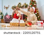cute cheerful children with an open smile, brother and sister, open golden gift boxes tied with red ribbon. children laugh and hold gifts in their hands. Christmas tree in light garlands in background