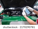 Professional mechanic and check car engine with computer diagnostic software.Expertise mechanic working in automobile repair garage.