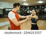 Small photo of beautiful young woman doing spanking motion with male instructor during body combat training