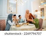 Small photo of group of Muslim friends clapping happily when one of their friends is given a surprise gift at the dinner table