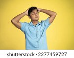 Small photo of young Asian man standing with giddy expression in isolated background