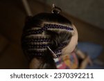 The master demonstrates to his students how to weave  braid with Kanekalon on a model, afro-locks on a frame, frame hairstyles, afro-curls, a base for hair extensions, a thin braid is braided over a g