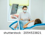 Small photo of Experienced female gynecologist in lab coat, face mask and gloves holding medical vaginal speculum for examining patient. Young woman lying on gynecological chair during check up.