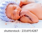 Small photo of Macro portrait of cute premature baby boy dressed in a blue knitted wool cap sleep, Neonatal intensive care unit in hospital. Child health, small newborn child lies in incubator