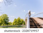 Woman walking on the pedestrian footbridge enjoying warm sunny weather, serene people and mental wellbeing concept.