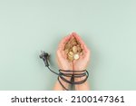 Female hands tied up with electric power cable cord holding Euro coins. Energy efficiency, power consumption, rising electricity price and expensive energy concept