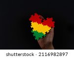 Black History Month background. African American history month celebration. Hand holding heart in red, yellow, green colors flag over black background