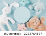 Babby kids toys collection. Empty round platform podium, teddy bears, white bunny and cute plush toys on light blue background. Top view, copy space
