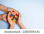 Small photo of Woman and child hands holding together colorful puzzle heart on light blue background. World autism awareness day, Autism spectrum disorder concept