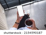 Top view mockup image of a woman holding mobile phone with blank screen and coffee cup