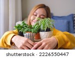 Portrait image of a beautiful young woman holding and hugging houseplants at home