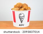 Small photo of Pruszcz Gdanski, Poland - August 23, 2021: Lots of KFC chicken hot wings in bucket of KFC (Kentucky Fried Chicken) fast food. Iconic bucket with Harland Sanders icon.