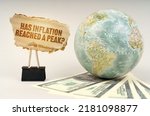 Business concept. On a gray surface, a globe, dollars and a cardboard plate with the inscription - Has inflation reached a peak