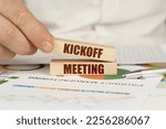 Small photo of Business concept. On the table are business charts and diagrams in the hands of a wooden block with the inscription - Kickoff Meeting