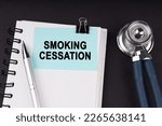 Small photo of Medical concept. On a black surface, a stethoscope, a notebook, a pen and a blue sticker with the inscription - Smoking Cessation