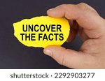 Business concept. On a black background, in the hands of a man, a yellow torn cardboard with the inscription - Uncover the Facts
